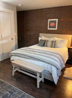 Ein Schlafzimmer mit einem Bett, einer Bank und einer Ziegelwand.