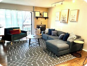 A living room with a sofa, a coffee table, and a fireplace. There are framed pictures on the wall. - OG Park City Vibe! 2 bedroom + hot tub (Park City)