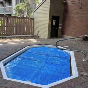 Ein Freibad mit einer Metallleiter und einem Holzzaun im Hintergrund.