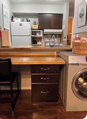 A compact kitchen with a wooden countertop, a built-in washing machine, and a dark wooden cabinet with drawers. - OG Park City Vibe! 2 bedroom + hot tub (Park City)