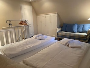 Ein Schlafzimmer mit zwei Betten, einem Kleiderschrank, einem Sofa und einem kleinen Tisch.