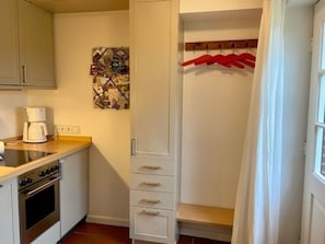 Eine kleine Küche mit Kaffeemaschine, Herd und Schrank.