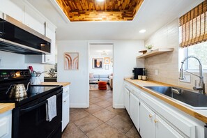 A modern kitchen with a black stove, white cabinets, and a wooden ceiling. - Hot tub I Fire pit I 10 min to park I 5 min to JT (Joshua Tree)