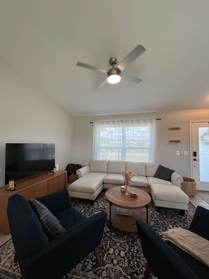 A living room with a sectional sofa, a coffee table, and a ceiling fan. - Cozy 3-bedroom home near Warm Mineral Springs, mayakka river, and gulf beaches (North Port)