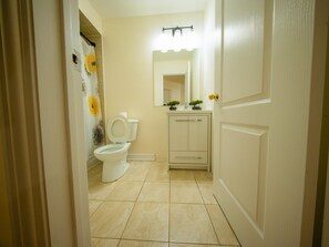 A bathroom with a toilet, a sink with a mirror, and a shower curtain. - 3-bedroom DUPLEX apartment in a serene environment Brampton, Canada (Brampton)