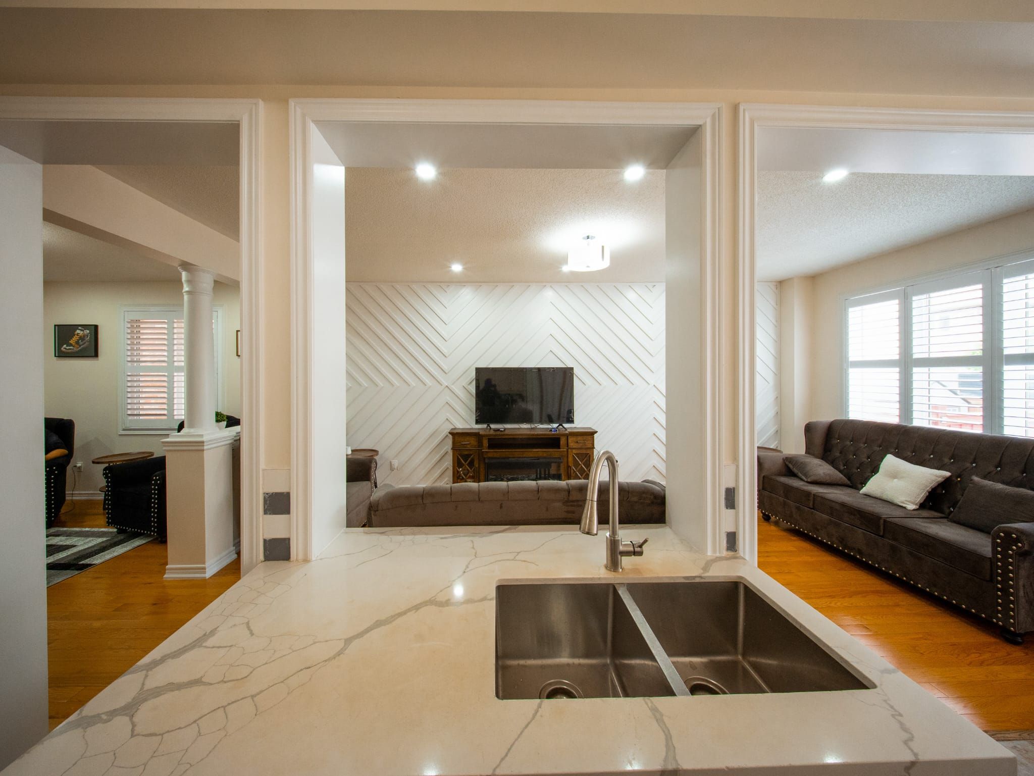 A modern kitchen with a central island, a built-in sink, and a herringbone-patterned wall.