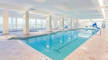 Une piscine intérieure avec des marquages bien visibles, un sol carrelé et de grandes fenêtres.