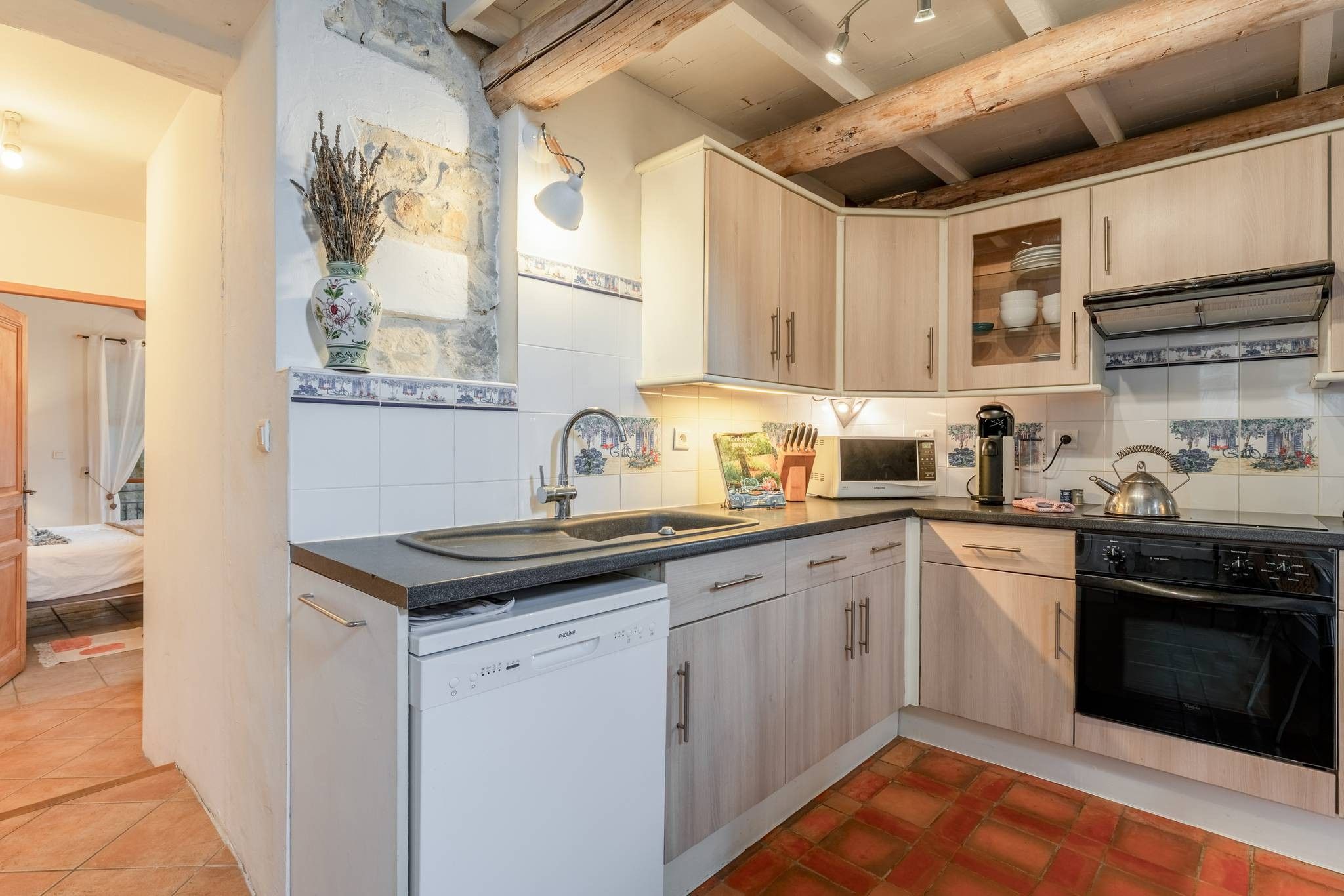 A compact kitchen with white cabinetry, a dishwasher, a microwave, and a stove.