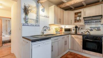 A compact kitchen with white cabinetry, a dishwasher, a microwave, and a stove.