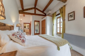 A bedroom with a large bed, wooden beams, a window with curtains, and a mirror. - Holiday Home 'Mas Bousquette' with Private Pool, Private Terrace and Wi-Fi (Lussan)