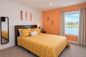 A bedroom with a large bed, a view of a body of water, and a cityscape in the distance. - 3BR Townhome / Game Room & Pond Views / 5-Min Drive to Beach / PCB (Panama City Beach)
