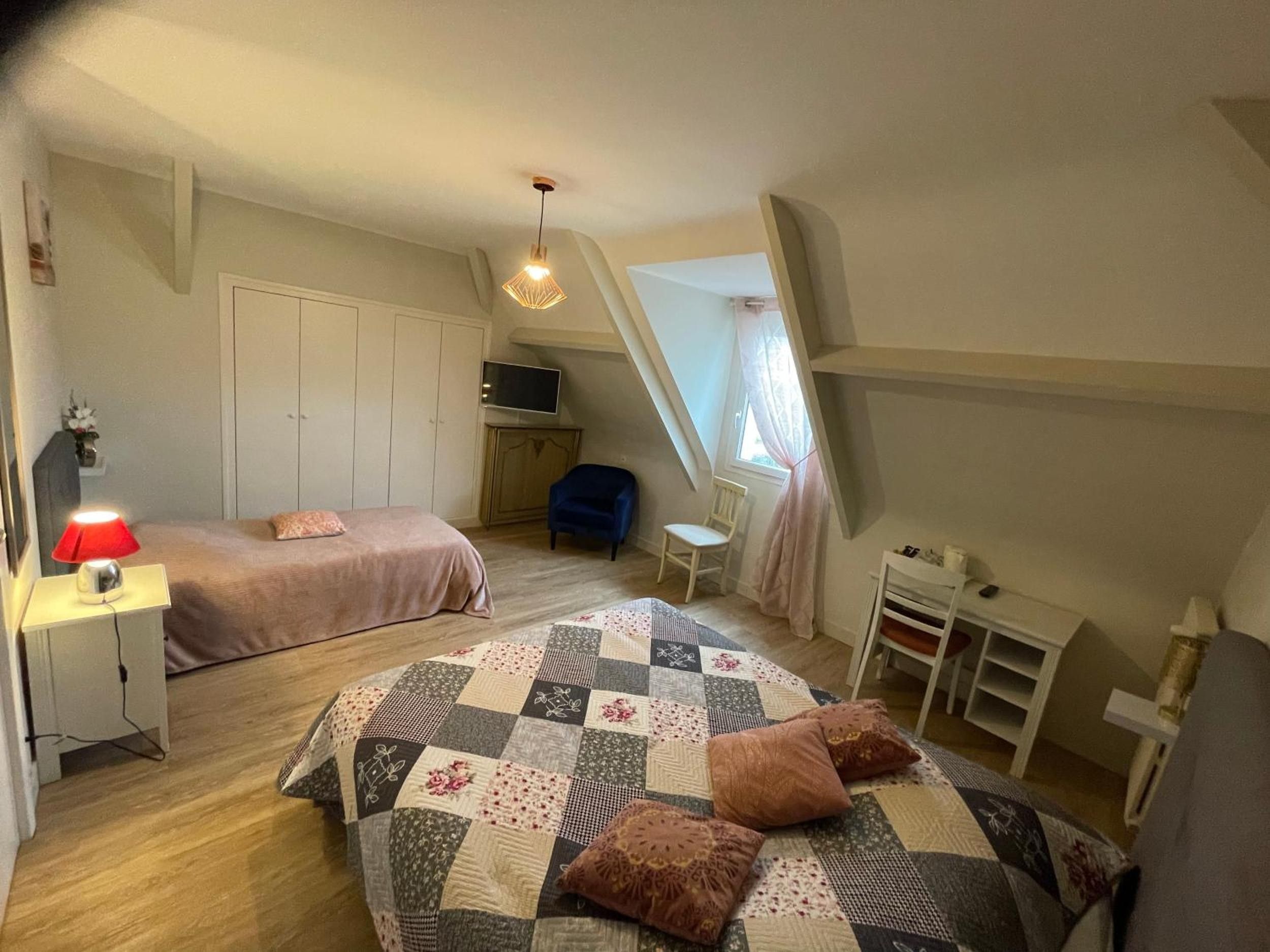 Une chambre avec deux lits, un bureau, une chaise, une télévision et une fenêtre avec des rideaux.