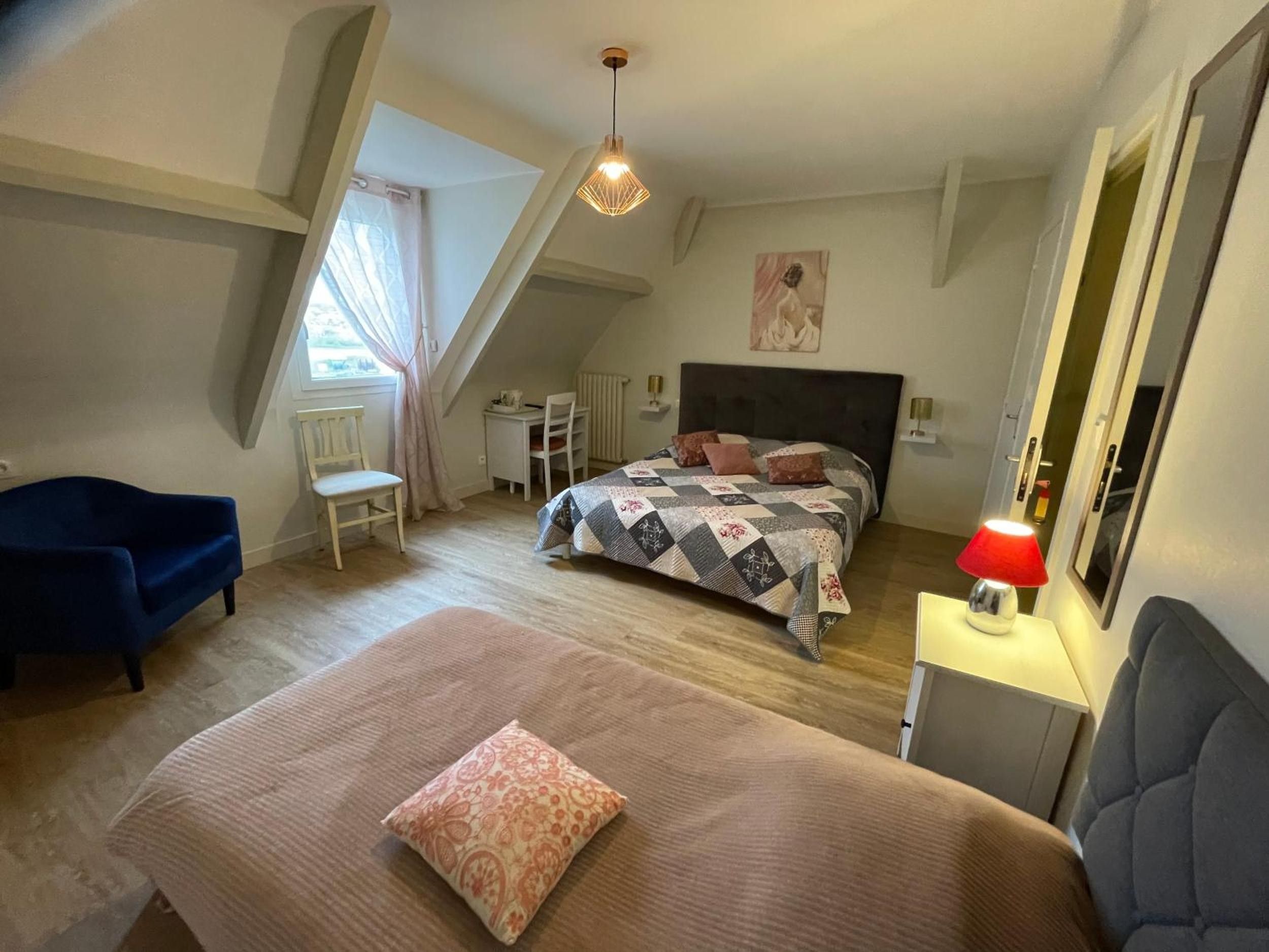 A bedroom with a bed, a desk, a chair, a sofa, and a lamp.