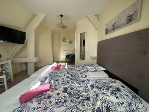 Una habitación de hotel con cama, televisión, escritorio y silla.