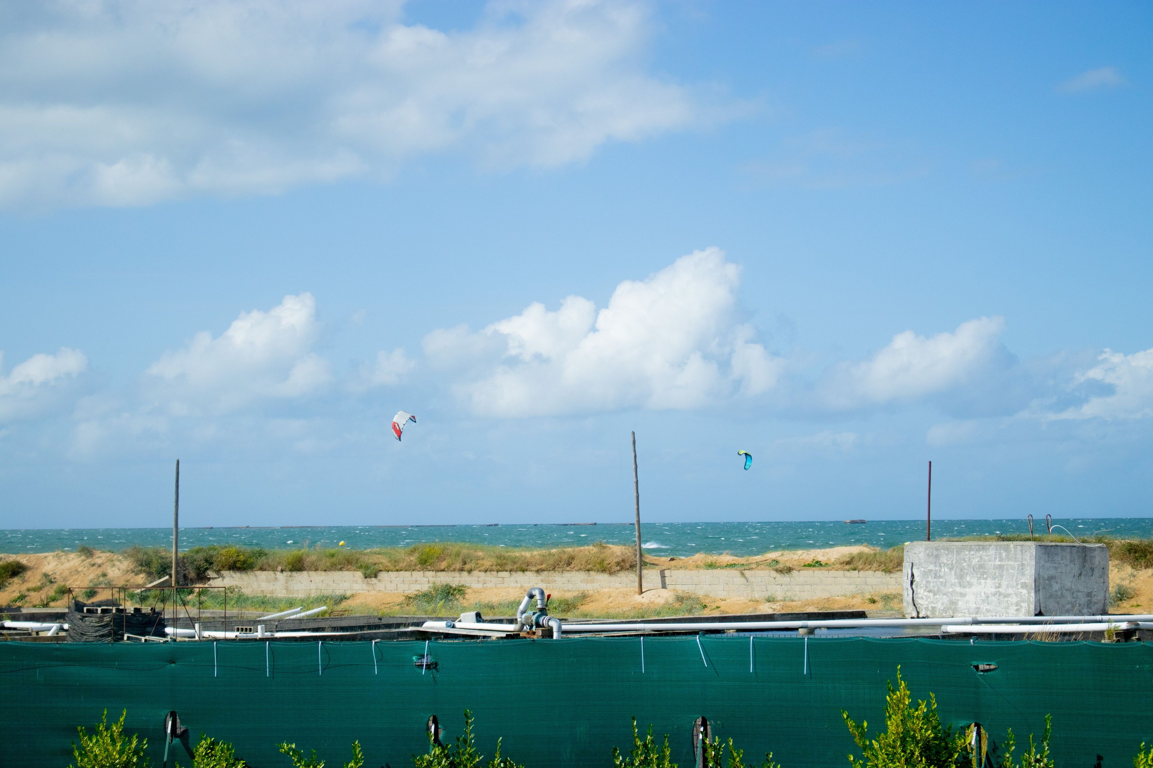 Een kustgezicht met heldere lucht, een zandstrand en een wateroppervlak.