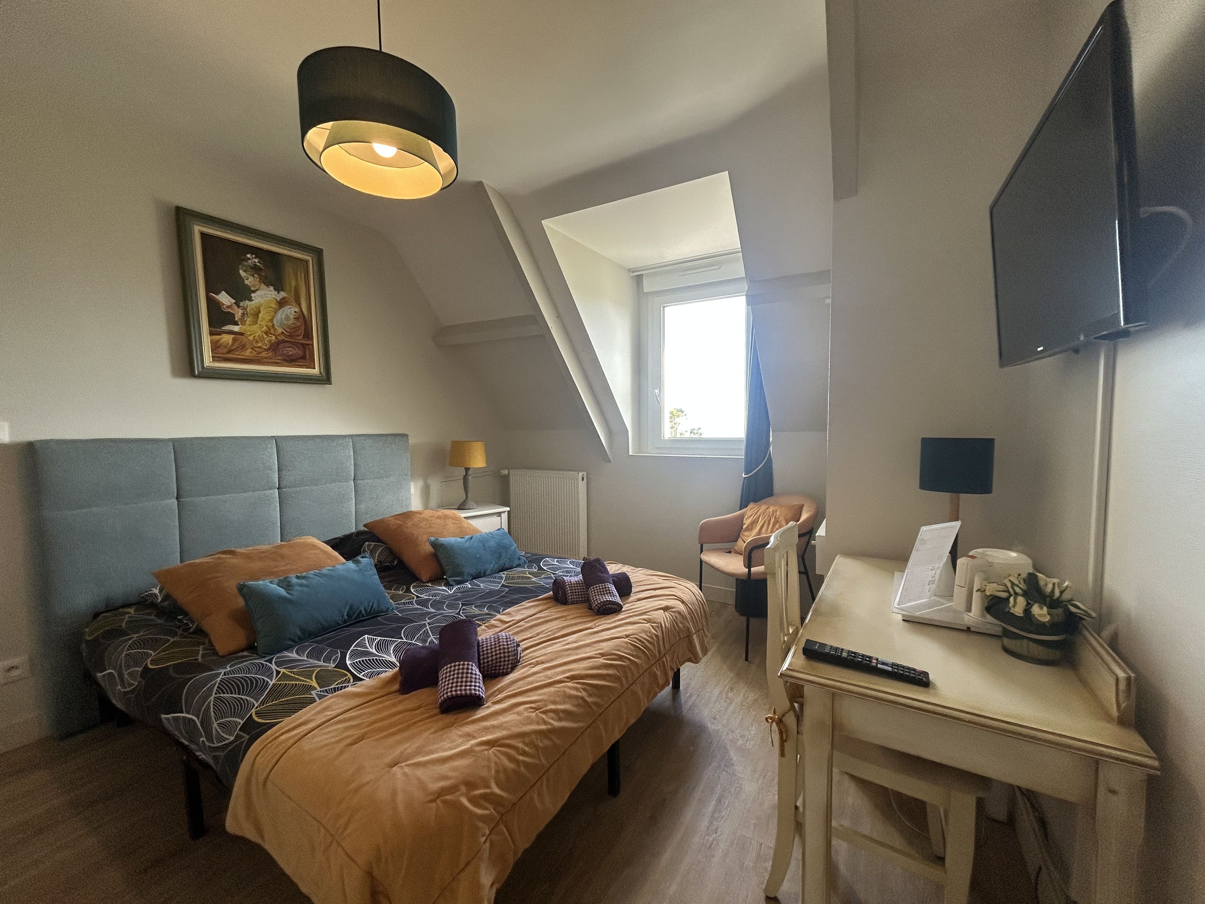 Une chambre à coucher avec un lit, un bureau, une chaise, une télévision et une fenêtre.