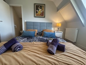 Una cama bien hecha con cubrecama estampado, almohadas y toallas enrolladas.