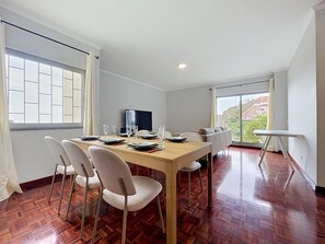Een eetgedeelte met een houten tafel, stoelen en een televisie.