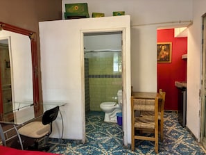 Een badkamer met betegelde vloer, toilet, stoel en spiegel.