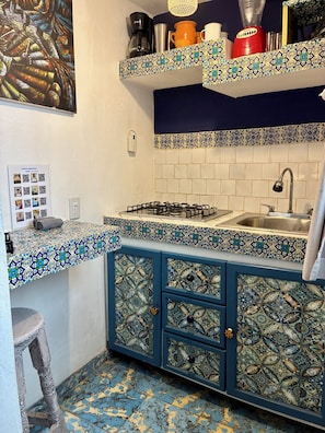 Een keuken met patroontegels, een gasfornuis en een spoelbak.