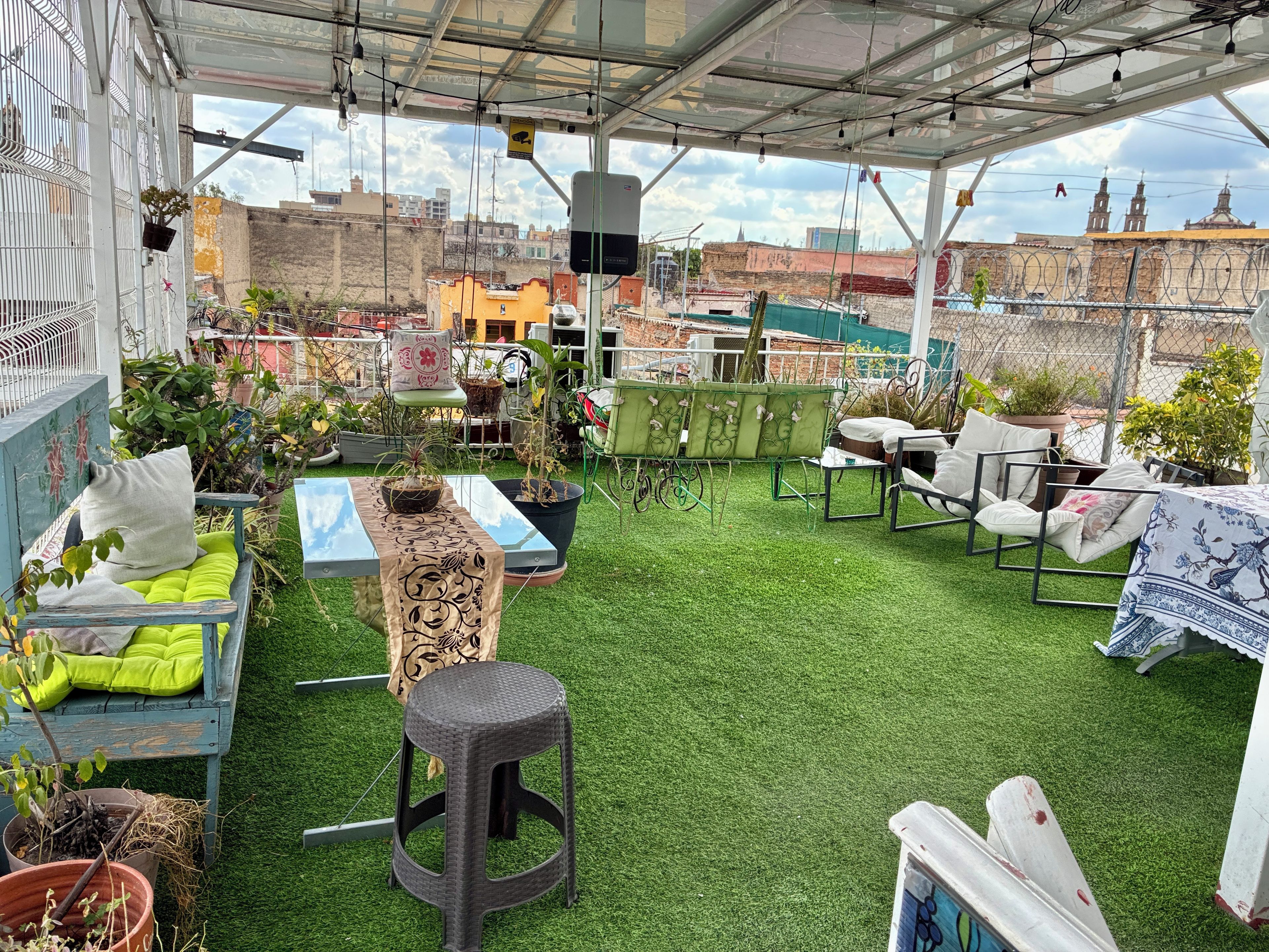 Une terrasse extérieure avec un revêtement de gazon synthétique, des espaces aménagés pour s’asseoir et des plantes en pot.