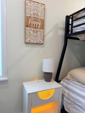 A bunk bed with a headboard, a bedside table with a lamp, and a wall decoration with a motivational quote. - Cozy Coastal 2 BDR Condo w/Parking Wildwood Crest (Wildwood Crest)