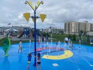 A water play area with multiple water jets and a slide, surrounded by a playground with various equipment. - Cozy Coastal 2 BDR Condo w/Parking Wildwood Crest (Wildwood Crest)