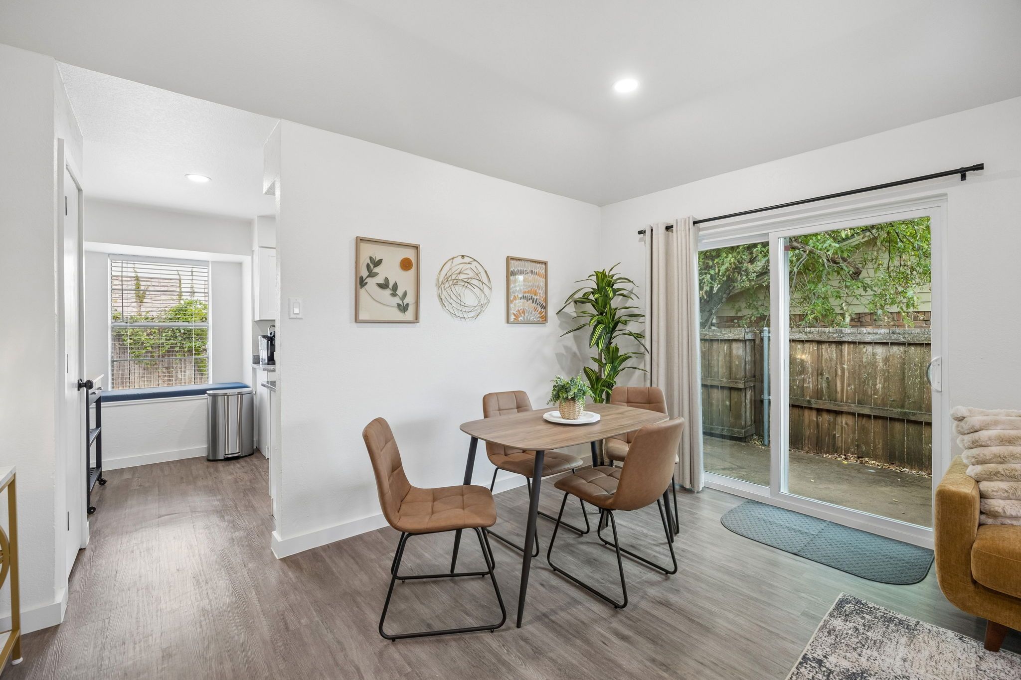A dining area with a table and chairs, a potted plant, and a sliding glass door leading to a backyard.