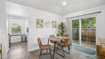 A dining area with a table and chairs, a potted plant, and a sliding glass door leading to a backyard.