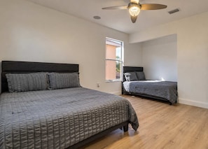 A bedroom with two beds, a ceiling fan, and a window. - Gated 4BR Oasis | Private Pool & Spa Near Disney (Kissimmee)