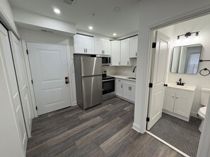 A modern kitchen with white cabinets, stainless steel appliances, and a patterned floor. - Studio apartment in welcoming Washington with AC and comfort. (Washington)