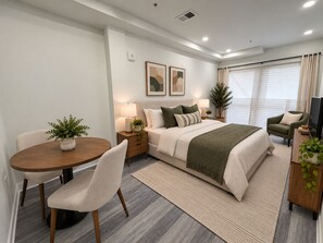 A modern bedroom with a bed, bedside tables, a desk, and a chair. - Studio apartment in welcoming Washington with AC and comfort. (Washington)