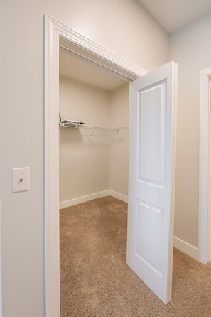 A room with beige carpet, a white door, and a closet with a hanging rod. - Across from UAB | Spacious 2BR Retreat 33b (Birmingham)