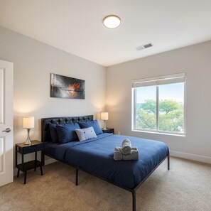 A bedroom with a bed, two bedside tables, a nightstand, a window with a view, and a ceiling light. - Across from UAB | Spacious 2BR Retreat 33b (Birmingham)