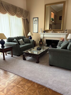 A living room with a sofa set, a glass coffee table, a fireplace, and a large mirror. - 3 Bedroom, 3 Bath home overlooking the 11th fairway on sunset Hill Golf Course (Thousand Oaks)