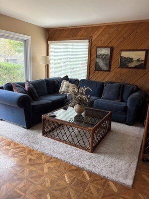 A living room with a dark blue sofa, a glass coffee table, and a patterned rug. - 3 Bedroom, 3 Bath home overlooking the 11th fairway on sunset Hill Golf Course (Thousand Oaks)