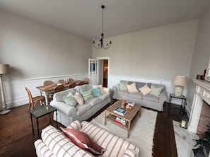 A living room with two sofas, a coffee table, a dining table with chairs, a chandelier, and a fireplace. - Union | Central 3 Bedrooms | Grand Stay | Sleeps 6 (Edinburgh)