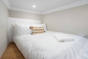A neatly made bed with white bedding and a decorative pillow, a wooden floor, and a white ceiling with a recessed light. - Union | Central 3 Bedrooms | Grand Stay | Sleeps 6 (Edinburgh)