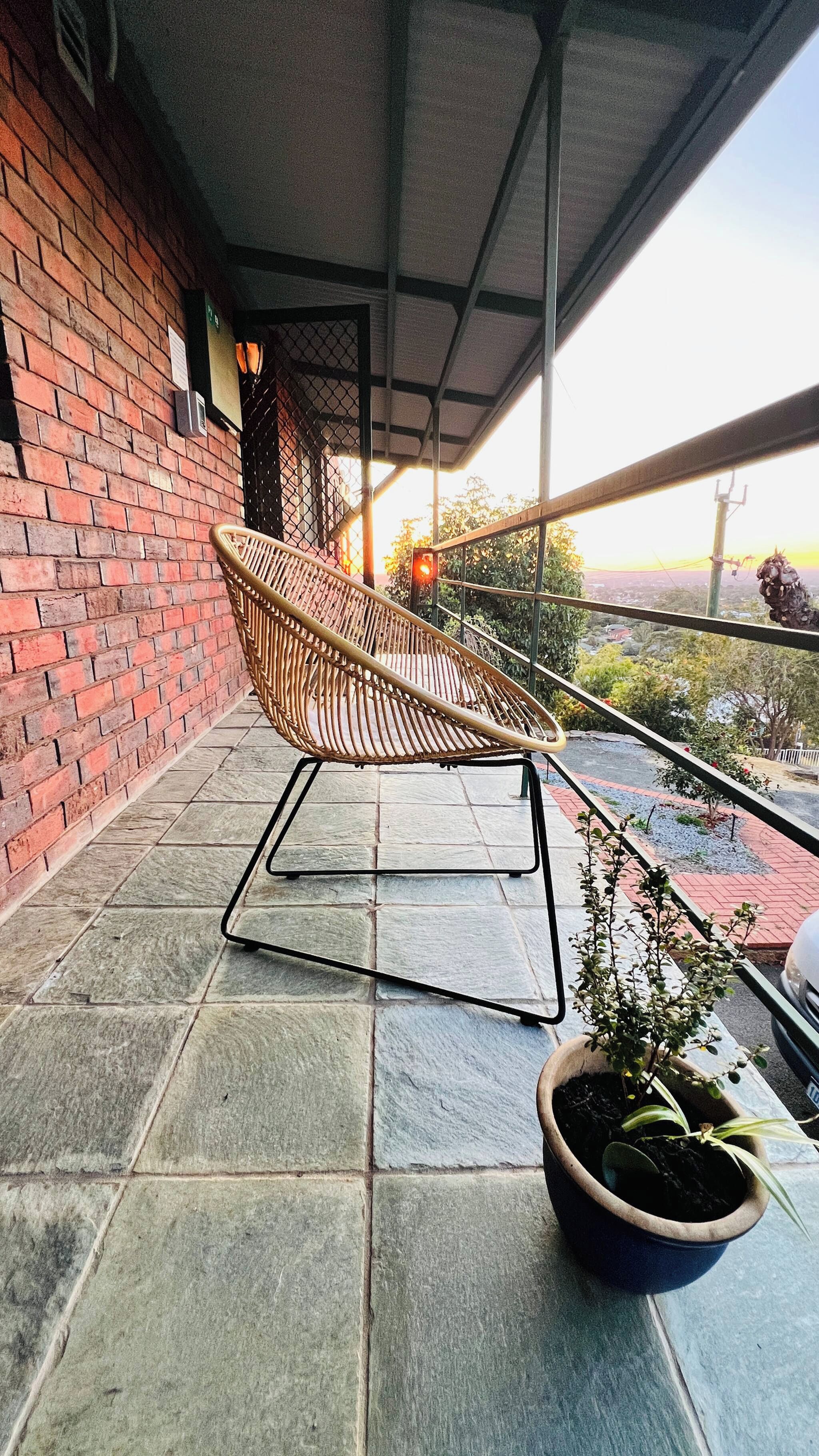 A wicker chair on a balcony with a potted plant.