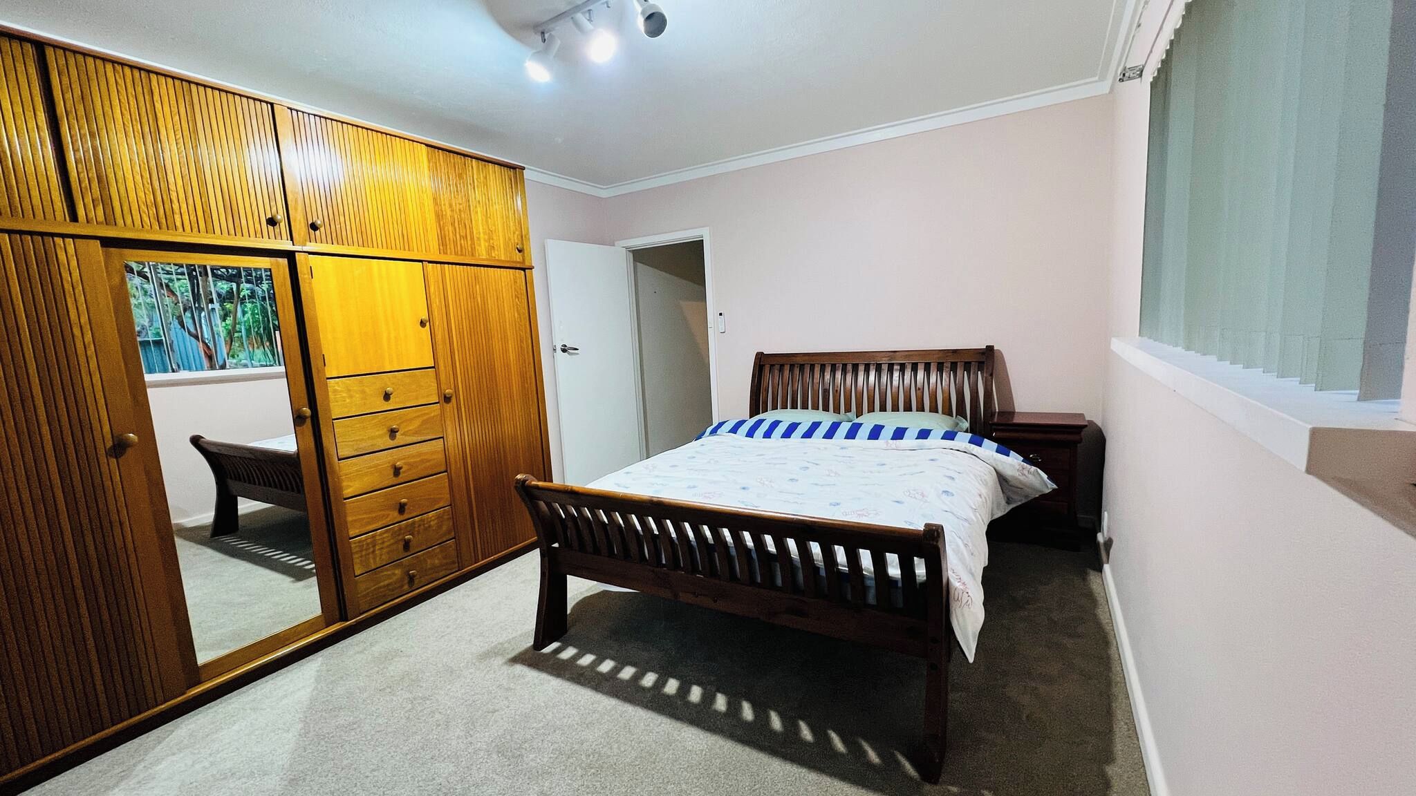 A bedroom with a bed, a wardrobe, a mirror, and a window.