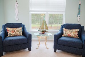 A room with two blue armchairs, a glass table with a decorative item, and a view through a window. - 5 Miles from Sunset Beach with a Pool and Golf Course Views (Sunset Beach)