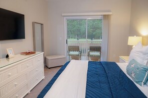 A hotel room with a bed, a dresser, a television, a balcony with chairs, and a window. - 5 Miles from Sunset Beach with a Pool and Golf Course Views (Sunset Beach)