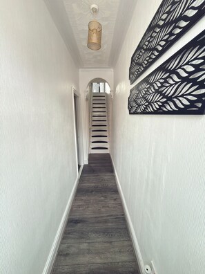 A hallway with a wooden floor, white walls, and a ceiling with a decorative pattern. - Where Comfort Meets Space-For Families, Council Relocations & Work Stay-Parking (Doncaster)