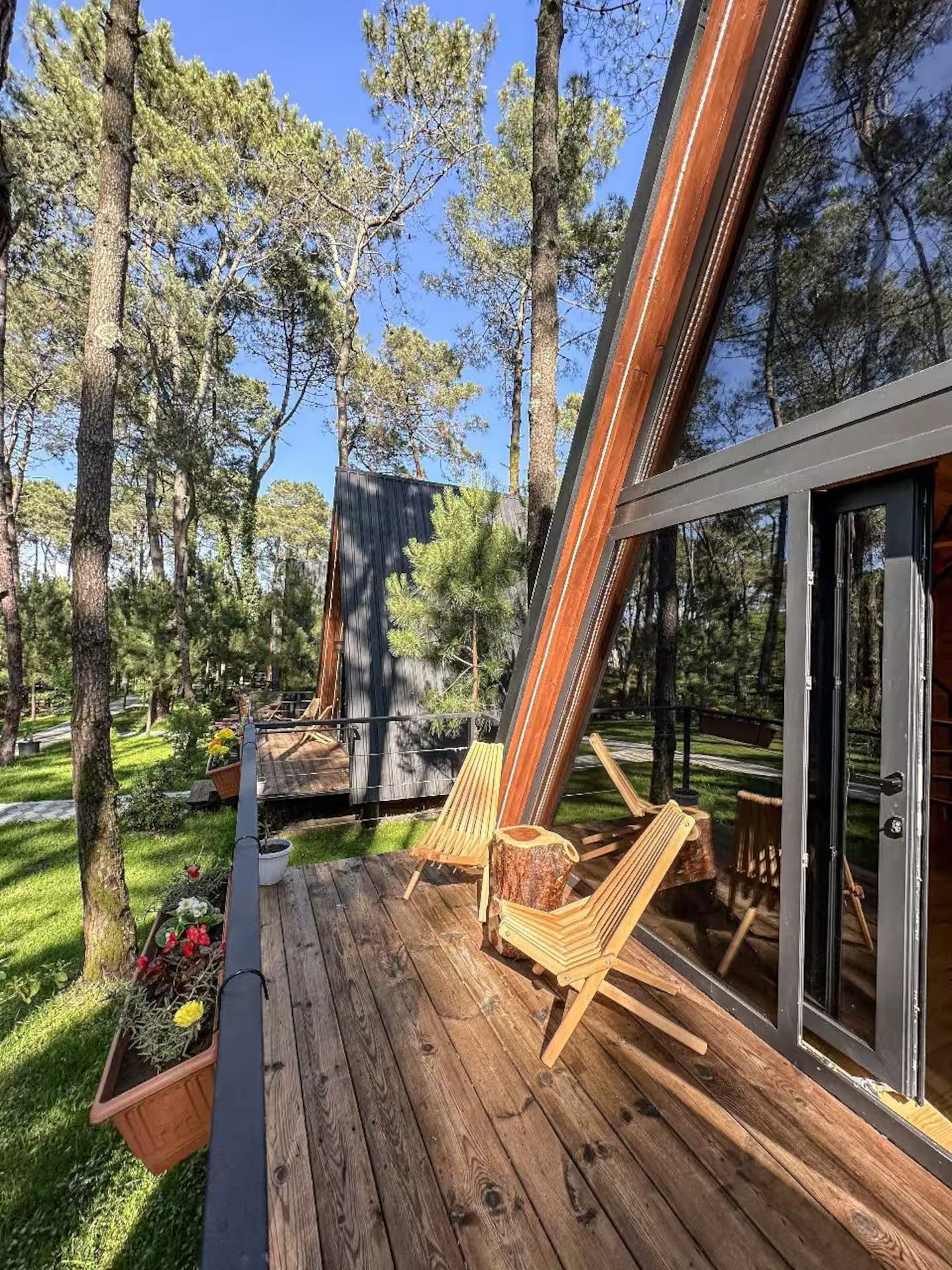 A deck with wooden flooring, two wooden chairs, and a glass door leading to a covered area.