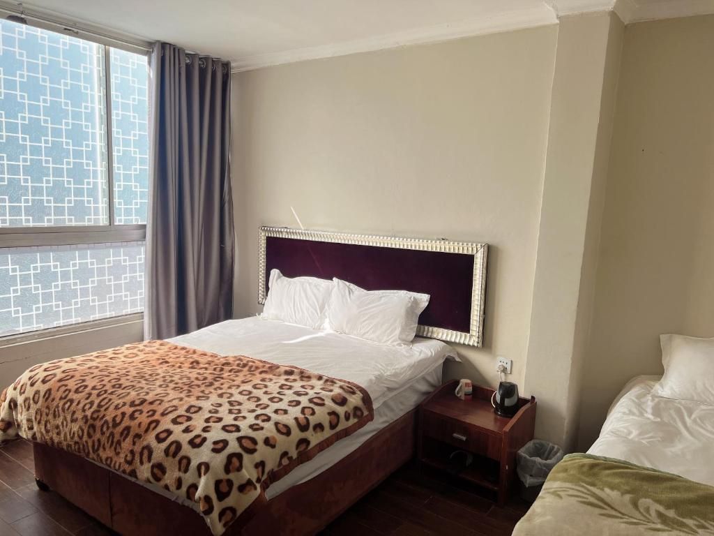 Habitación de hotel con cama, mesita de noche, ventana con cortinas y vista al exterior.