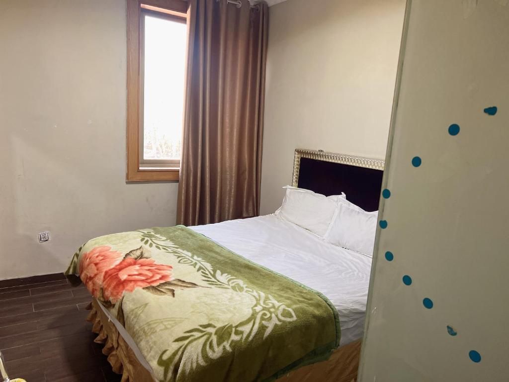 A bedroom with a bed, a window with curtains, and a wall with a pattern.
