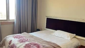 Una camera da letto con un letto, un comodino, una finestra con tende e vista sull'esterno.
