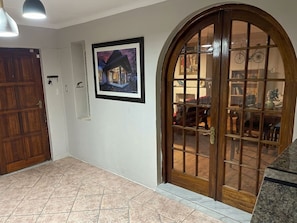 A hallway with a wooden door, a framed picture on the wall, and a glass door leading to a room with furniture. - Shengtang Business Hotel (Johannesburg)