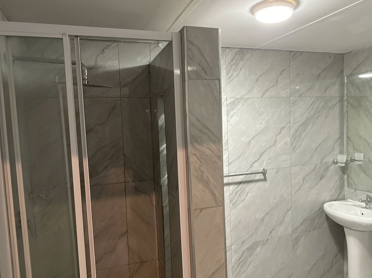 Un baño con cabina de ducha, lavamanos y espejo.