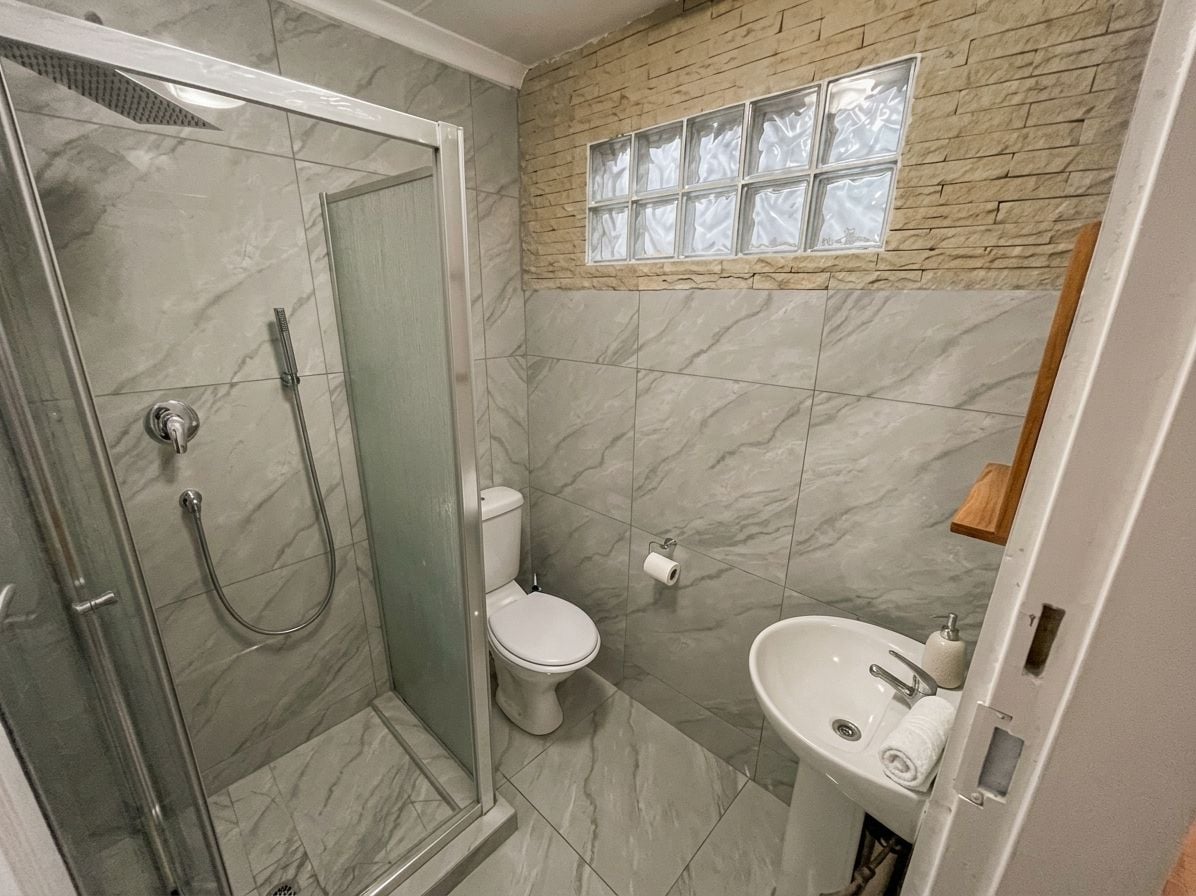 A bathroom with a glass-enclosed shower, a toilet, and a sink.